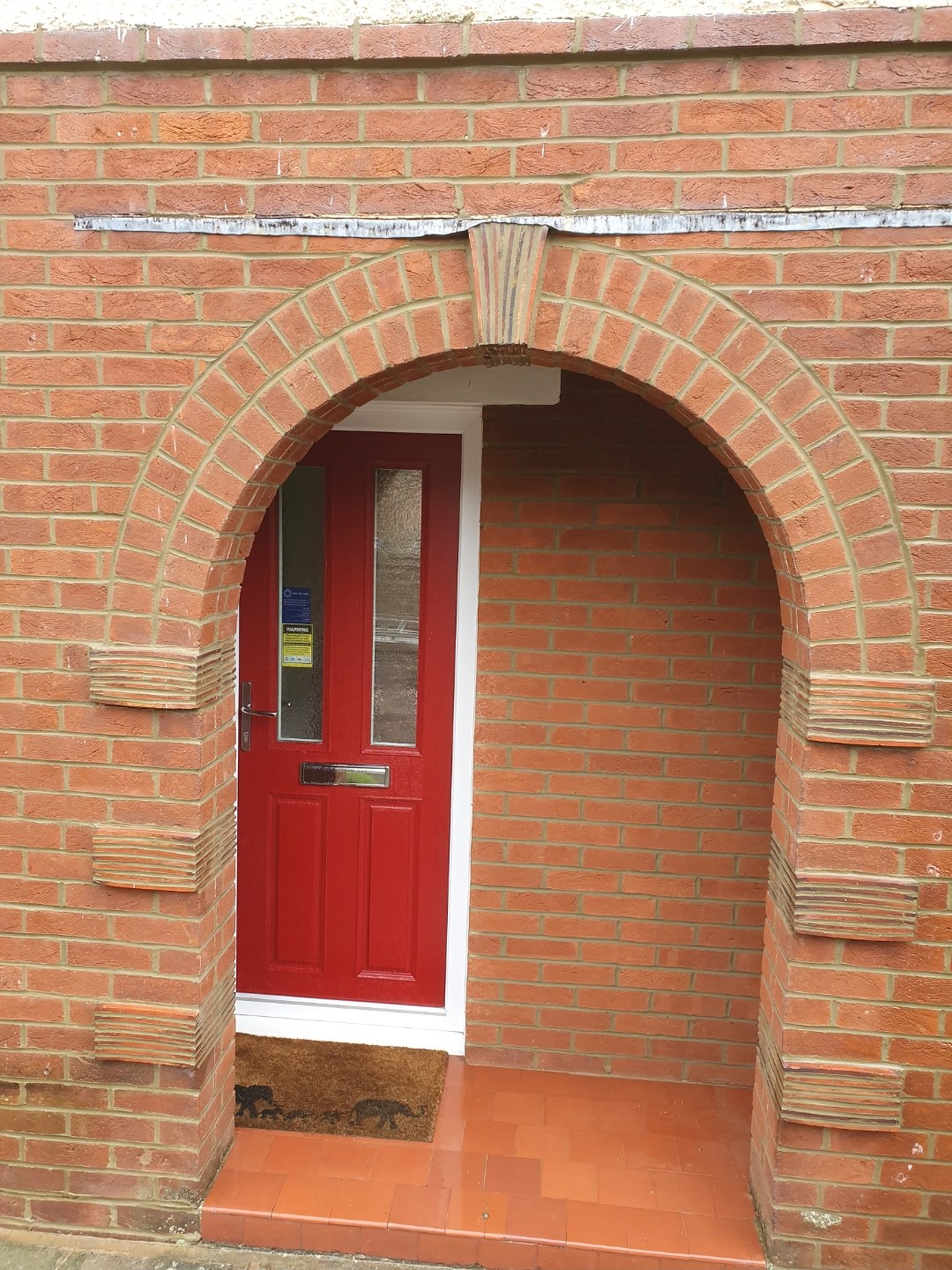 Brick arch porch with a red front door, brickwork finished by Chaplin