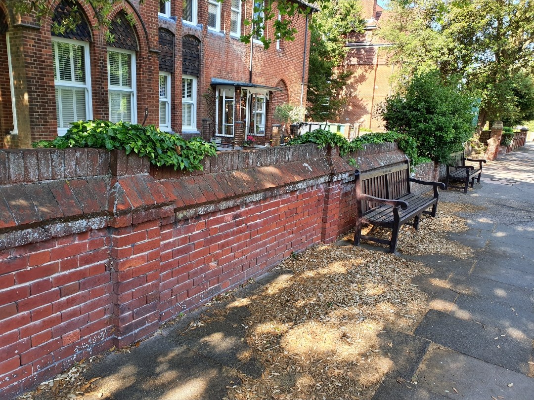 Long red-brick boundary wall beside a footpath