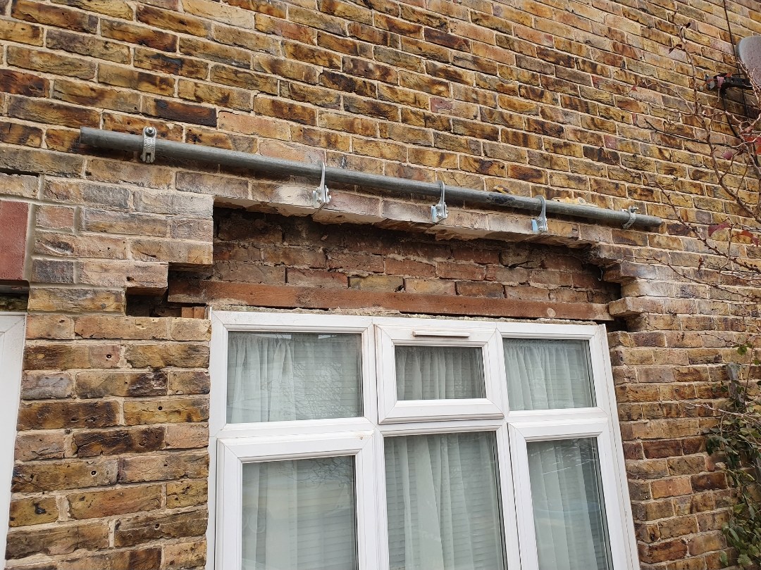 Joints raked out around a window lintel ready for repointing